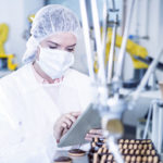 Time to work Smart Woman in factory using tablet with robot handling cookies