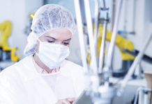 Time to work Smart Woman in factory using tablet with robot handling cookies