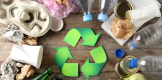 Recycling symbol and different garbage on wooden background, top view
