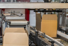 Cardboard box of product packaging is moving on conveyor belt of automatic packing machine