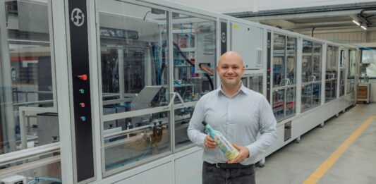 Fruglapac Product Director JP Grogan and the new Frugal Bottle Assembly Machine 2 (FBAM-2)